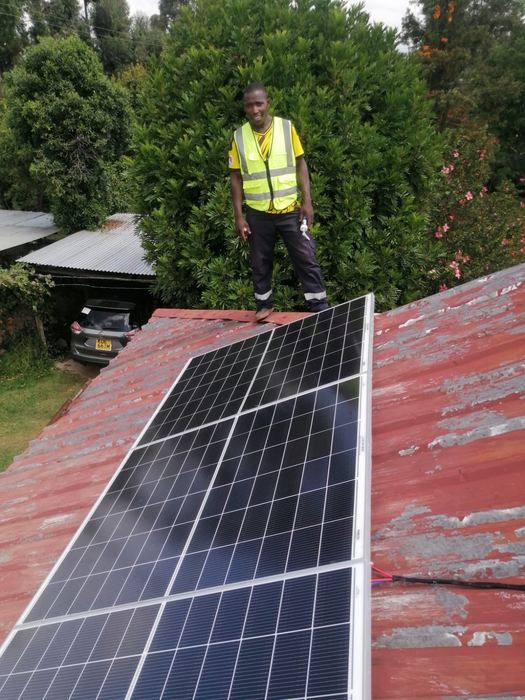 Technician standing on a roof beside newly installed solar panels